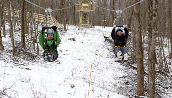 2 people ziplining in the winter 