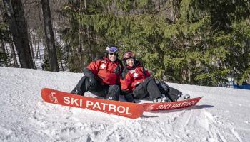 2 ski patrol sitting on the mountain